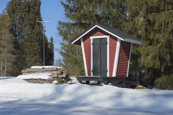 Old traditional wooden, milk dock that were used to hold milk containers to wait for milk delivery truck in winter with snow covering the ground, Suurikylä, Finland