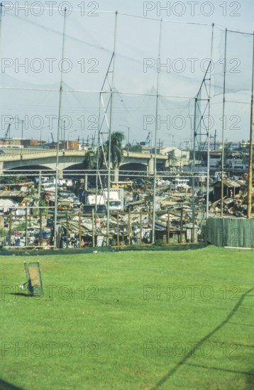 Green lawn of a sports field, slums behind it, Manila in 1995, Philippines