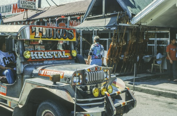 Jeepney minibus in front of a restaurant with skewered suckling pig, Lechon, Manila in 1995, Philippines