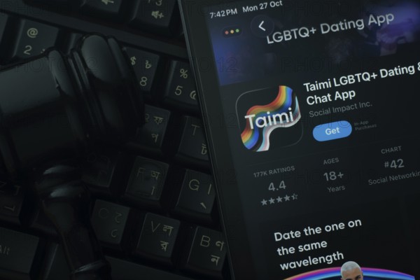 Dhaka, Bangladesh- 28 Oct 2025: An iPad displaying the Taimi app against a judge's gavel and dark keyboard background