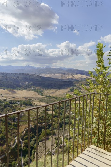 Ronda, malaga, spain Viewpoint balcony overlooking the vast valley with mountains and fields under a blue sky with clouds in ronda, andalusia