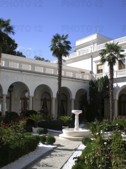 The Italian Courtyard, with its unique, luxurious architectural style, is a cozy, picturesque promenade area of ??the Livadia Palace. It includes a fountain and an alley lined with palm trees. Windows from one of the palace buildings overlook it. A popular tourist destination for many travelers, it was once admired by members of the Russian nobility and the royal families of the Russian Empire. Livadia, Crimea, Ukraine
