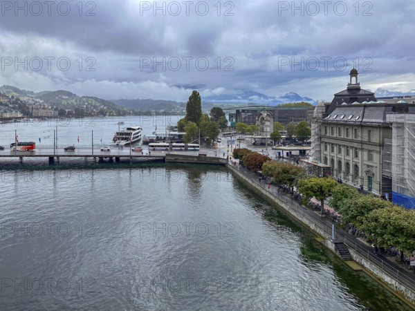 View of waterfront with boats and mountains in the background under cloudy sky, Lucerne, Switzerland