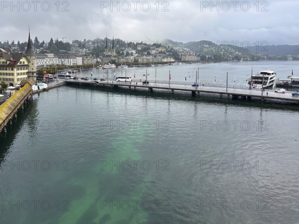 Harbour view with boats, buildings and hills in the background under cloudy sky, Lucerne, Switzerland