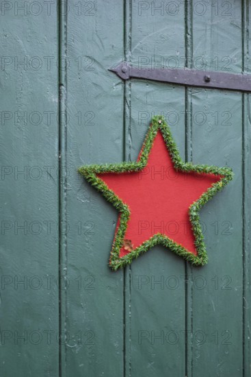 Red star with green border on green wooden door, festive decoration, North Rhine-Westphalia, Germany