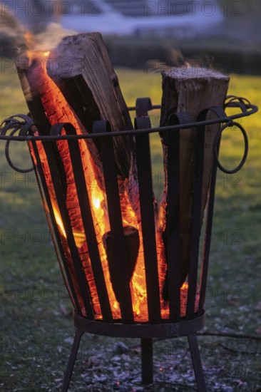 Burning logs in a fire basket create a warm, cozy atmosphere at dusk, North Rhine-Westphalia, Germany
