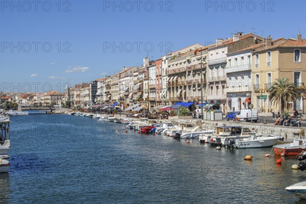 View from Pont de la Savonnerie of the Canal de Sete (formerly Canal Royal) with the elegant, historic house facades of Quai Leopold Suquet and moored boats under a blue sky in Sete, Venice of Languedoc, Herault department, Occitanie region, France