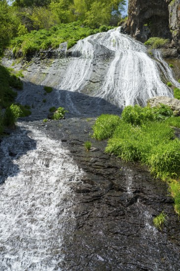 A steep stream flows through rocks and green plants, in the heart of a natural landscape, Jermuk Waterfall, Vayots Dzor Province, Vayots Dzor, Armenia