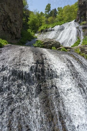 Two waterfalls flowing over rocks surrounded by green vegetation in sunny nature, Jermuk Waterfall, Vayots Dzor Province, Vayots Dzor, Armenia