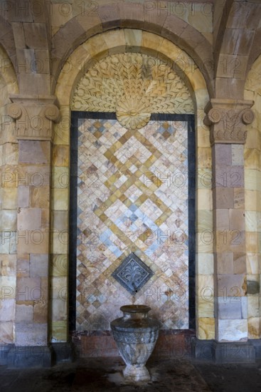 Detailed mosaic with decorative patterns and reliefs on the wall above a stone jug, spring, mineral water gallery in Jermuk, mineral spring, health resort, Wajoz Dzor province, Vayots Dzor, Armenia