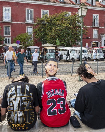 Street art, young people with Ronaldo mask on the back of their heads taking part in a school project about drawing, Lisbon, Portugal