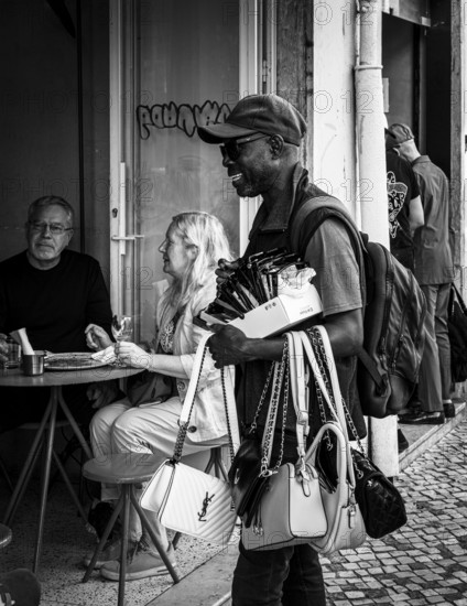 Black and white photography, street art, retailer offering his goods, Lisbon, Portugal