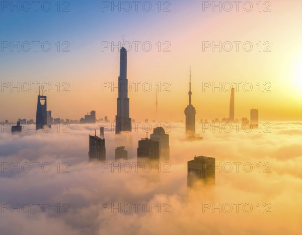 City scape emerging from a dense enveloping fog in sunrise and skyscrapers piercing the haze, big metropolis with skyline, mist on ground, blue sky, city in an aerial view, AI generated