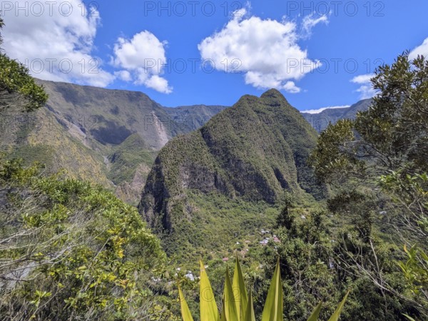 Scenic view of lush green mountains under a bright blue sky with scattered clouds, La Réunion, France