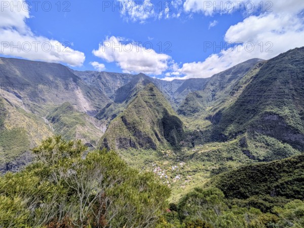 Majestic mountains with lush greenery under a bright blue sky and scattered clouds, La Réunion, France