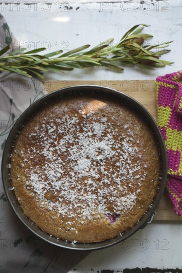 Coconut cake in an antique baking dish on a wooden board
