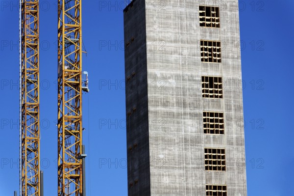 Two yellow cranes on skyscraper construction site of timber building Kaj 16 with hybrid concrete frames, sunny day, Lilla Bommen area, Gothenburg, Sweden