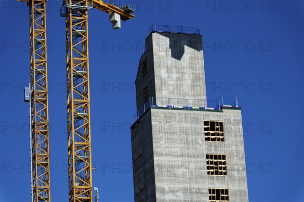 Yellow cranes on construction site of timber building Kaj 16 with hybrid concrete frames, sunny day, Lilla Bommen area on May 12, 2025 in Gothenburg, Sweden