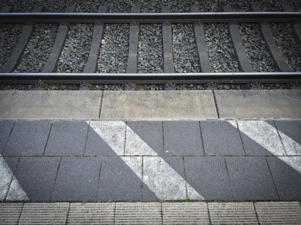 Station tracks with gravel bed, adjacent asphalt and eye-catching strip markings, platform in 27798 Hude, Lower Saxony, Germany