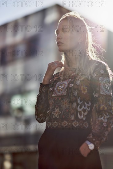 Elegant designer woman in sunlight in front of futuristic modern architecture house, apartment buildings, future oriented, pondering about future, making plans, calmly feeling sensation, fashion design, architecture student, fashion design student, design student, relaxed, backlit, lens flare, sensitive, steadfast, curious, mindset, trends, youth, modernity, architectural design, designer, pensive, thinking, pondering, ideas, wistful remeniscing, beauty, attractive, fashion model, blond, dutch ethnicity