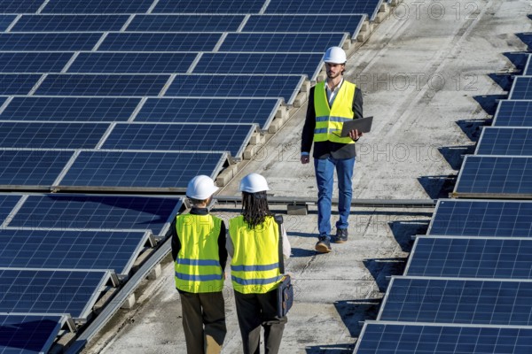 Engineers checking a large installation of solar panels on a commercial rooftop, ensuring optimal performance for sustainable energy generation and maintenance