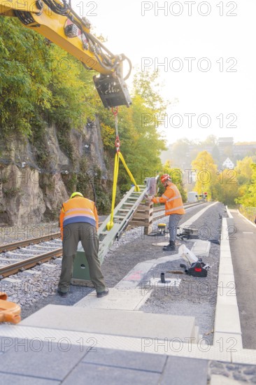 Workers install object on railroad tracks, surrounded by autumn trees, signal building on the Hermann Hessebahn, Calw, Germany