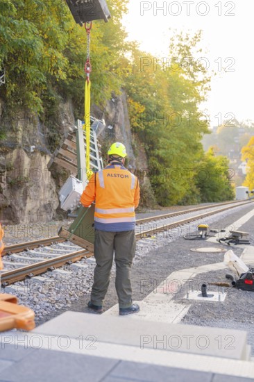 Workers wearing protective clothing on railroad tracks surrounded by autumn trees, signal building at Hermann Hessebahn, Calw, Germany