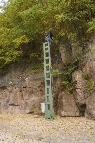 Green signal tower in front of rocky embankment with trees and safety net, Signalbau an der Hermann Hessebahn, Calw, Germany
