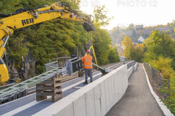 Track work with excavator, construction worker fixing objects, autumn urban landscape, signal construction on the Hermann Hessebahn, Calw, Germany
