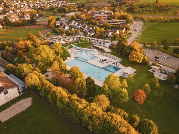 Aerial view of a swimming pool in a village surrounded by autumn trees, Calw, Black Forest, Germany