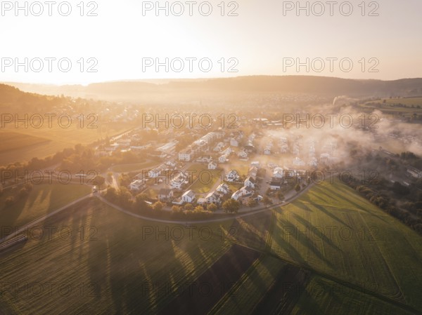 A small town surrounded by fields at sunrise with enchanting fog, Calw Stammheim, Black Forest, Germany