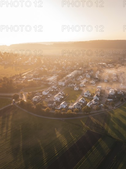 Village and fields in morning fog with warm shades of sunrise light, Calw Stammheim, Black Forest, Germany