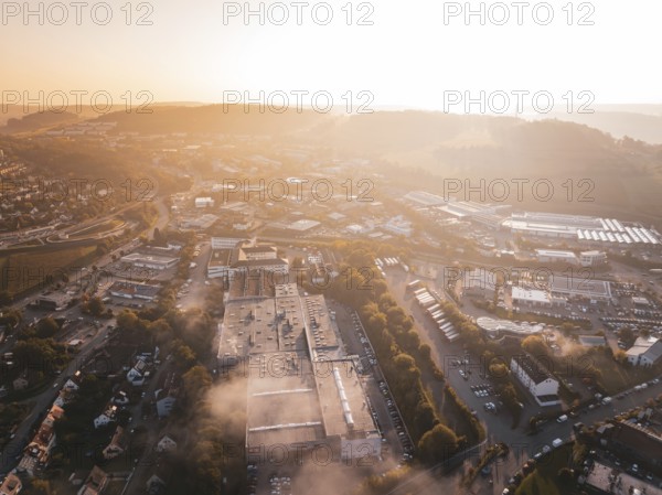 Aerial view of an industrial urban area and fields in orange morning fog, Calw Stammheim, Black Forest, Germany