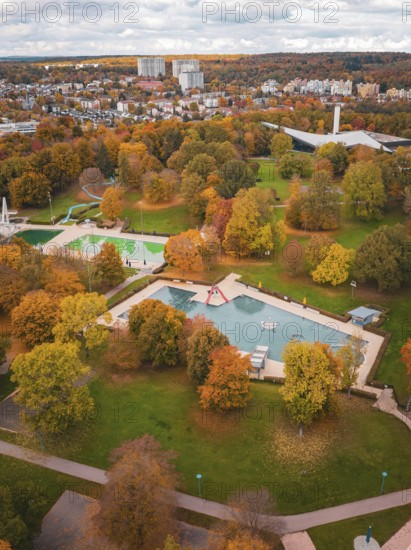Autumn park with large trees and pond, surrounded by urban architecture, Sindelfingen, Böblingen district, Germany