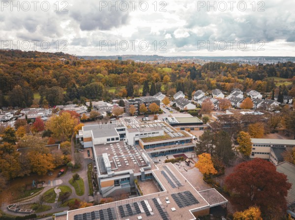 School building surrounded from above by autumn-colored trees and thick forest, Sindelfingen, Böblingen district, Germany
