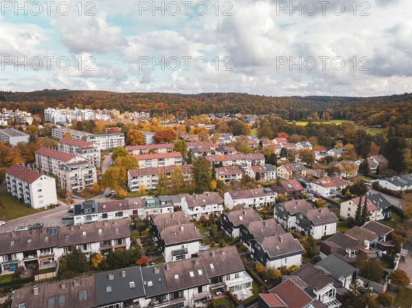Residential area with terraced houses and surrounding colorful autumn trees in slightly cloudy skies, Sindelfingen, Böblingen district, Germany