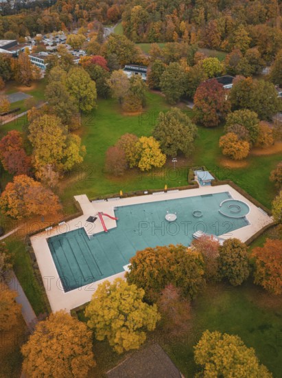 Small pond in an autumn park surrounded by colorful trees and trails, Sindelfingen, Böblingen district, Germany