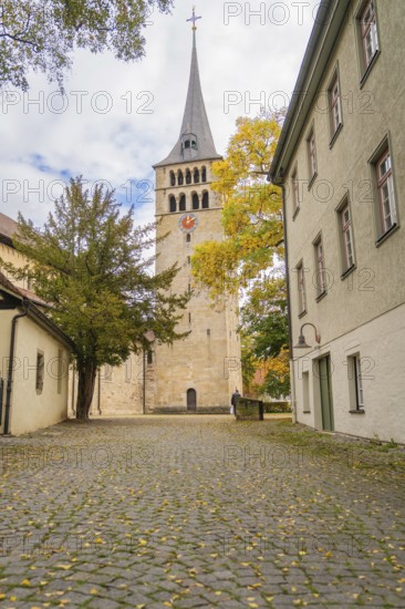 A narrow path leads to an old church tower with colorful autumn leaves, Sindelfingen, Böblingen district, Germany