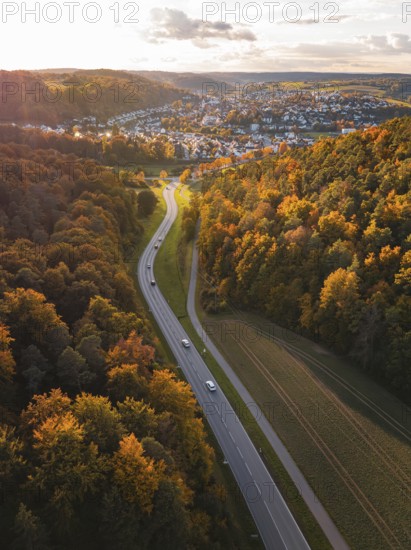 Road through autumn landscape with village in background during sunset, Aidlingen, Böblingen district, Germany