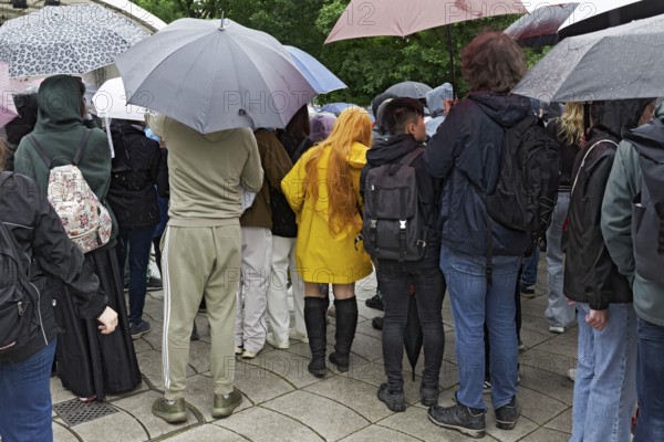 Young spectators with umbrellas in back view, woman with bright yellow rain jacket in between, Japan Day Düsseldorf, North Rhine-Westphalia, Germany