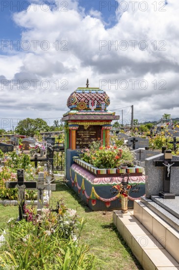 A colorful, richly decorated Hindu shrine with a small temple roof in the cemetery stands between many tombstones with Christian crosses, which underlines the multicultural diversity and religious tolerance of the French tropical island, Saint-Gilles-les-Hauts, La Reunion, France