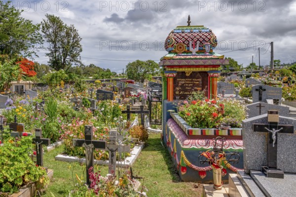 A colorful, richly decorated Hindu shrine with a small temple roof in the cemetery stands between many tombstones with Christian crosses, which underlines the multicultural diversity and religious tolerance of the French tropical island, Saint-Gilles-les-Hauts, La Reunion, France