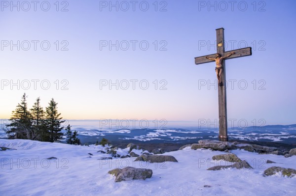 Christian cross on the peak of Mount Lusen with the view over the hills of the bavarian forest at sunrise at winter, Bavaria, Germany