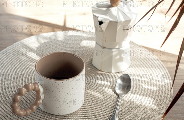 Making morning coffee, geyser coffee maker and mug, in bed colors, on a wooden table, natural light, no people