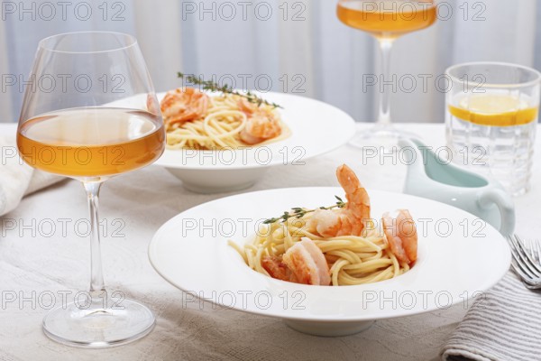 Pasta with shrimp and thyme, served on a white plate, with a glass of white wine, the table is set, Gourmet dinner, on a linen tablecloth, no people