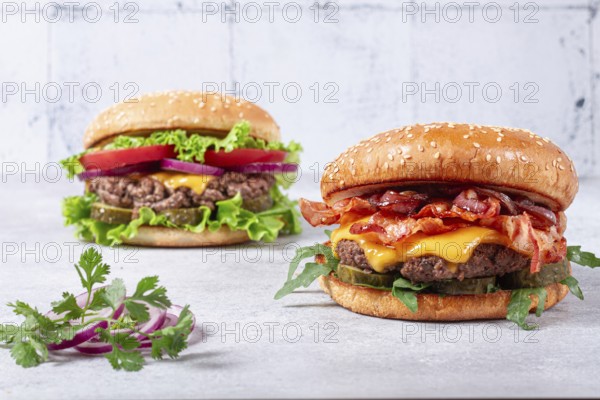 Two burgers with beef patty, fried bacon, cheddar cheese, tomatoes, homemade, no people