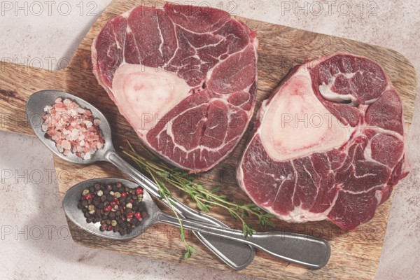 Knuckle on the bone, raw ossobuco meat, on a wooden chopping board, with spices, top view, no people