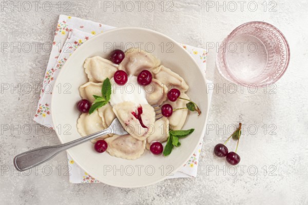 Traditional dumplings with cherries and yogurt, in a bowl, light background, close-up, no people