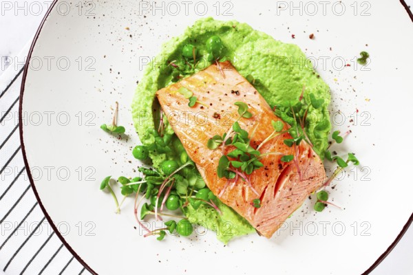 Delicious grilled salmon is placed elegantly on creamy green pea puree. Fresh microgreens and peas add a bright touch, creating an appetizing dish perfect for any meal
