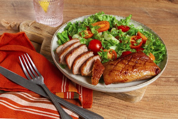 Delicious grilled duck breast served with fresh garden salad and cherry tomatoes at a rustic dining table